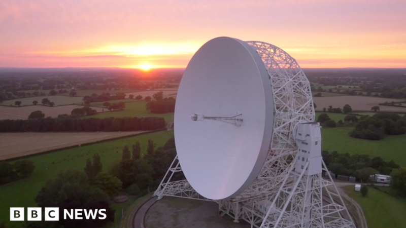 An aerial view at sunrise of the Lovell telescope at Jodrell Bank. Its huge white dish, taller than a house, is tilted