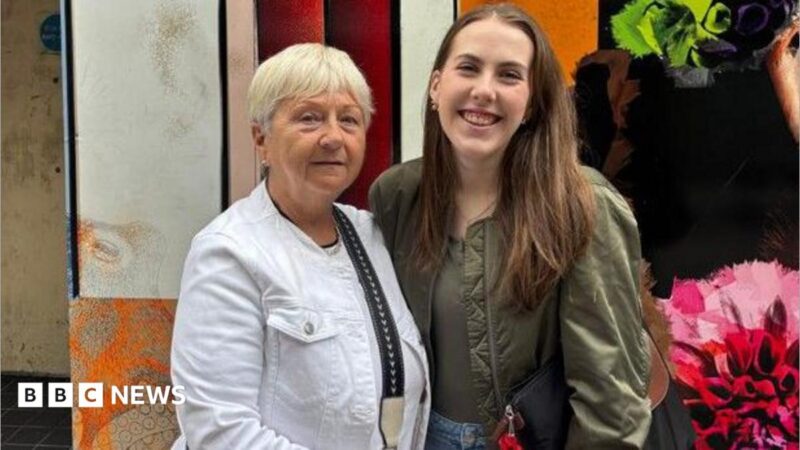 On the left is Agnes, wearing a white jacket, black jeans with a black and cream cross body bag. She has short blonde hair