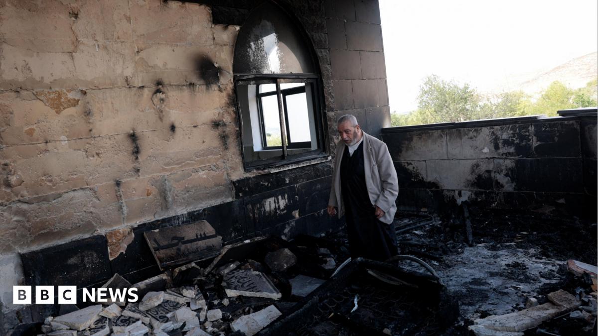 A Palestinian man inspects the damage at a mosque, which Palestinians say was damaged by Israeli settlers, in Qusra near