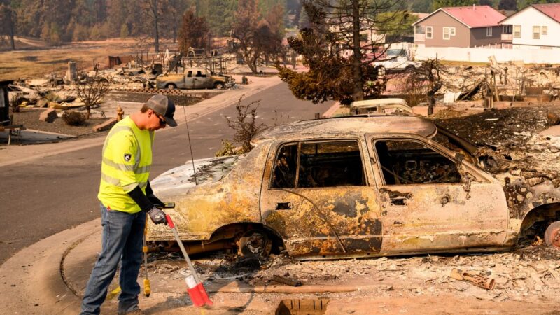 A utility worker marks a spot where a suspected gas line is at a burned property during the Old Trails fire in Spokane