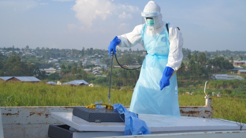 A health worker sprays the coffin containing the remains of Jacques Lobo Dhena, who died of Ebola, during a burial service