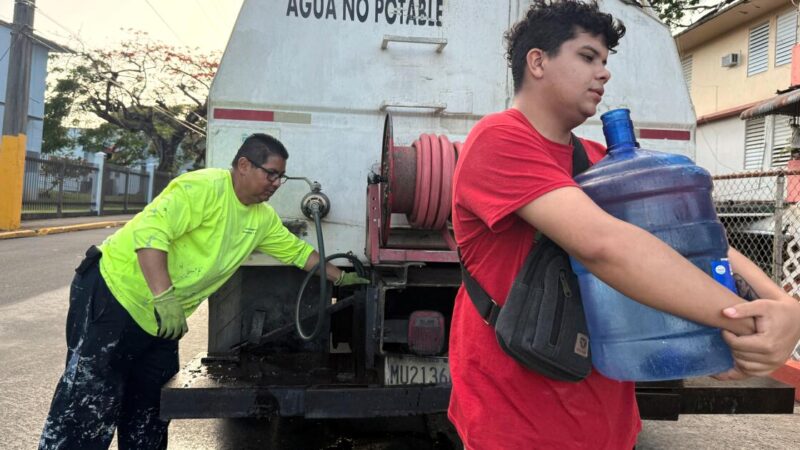 FILE - Bryan Pérez hauls a five-gallon water jug to his apartment in the Villa Kennedy public housing complex in San Juan