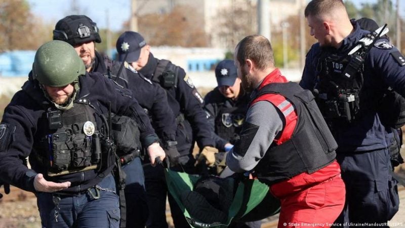 A paramedic and police officers carry a person injured at a railway station