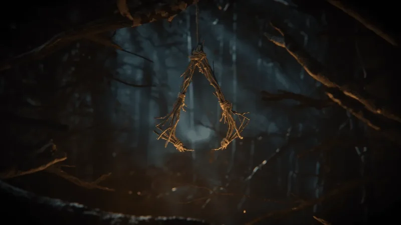 Assassin’s Creed Hexe teaser image showing the series logo made of twigs hanging in a dark forest (Image: Ubisoft)