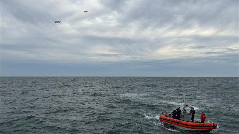 In this photo released by U.S. Coast Guard, crew members search by air and on the water for a Boston-bound air ambulance